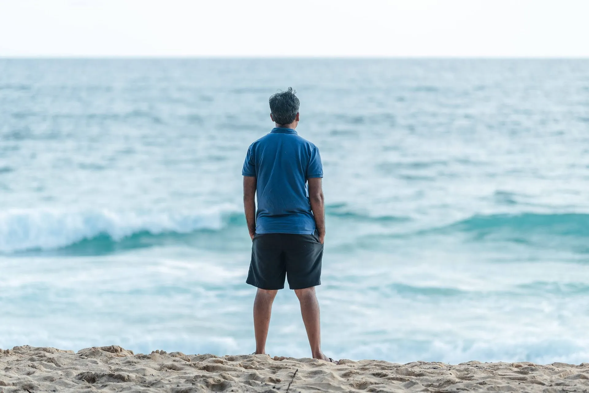 A builder surveys the Carova Beach coastline, assessing conditions for coastal construction in the 4x4 zone